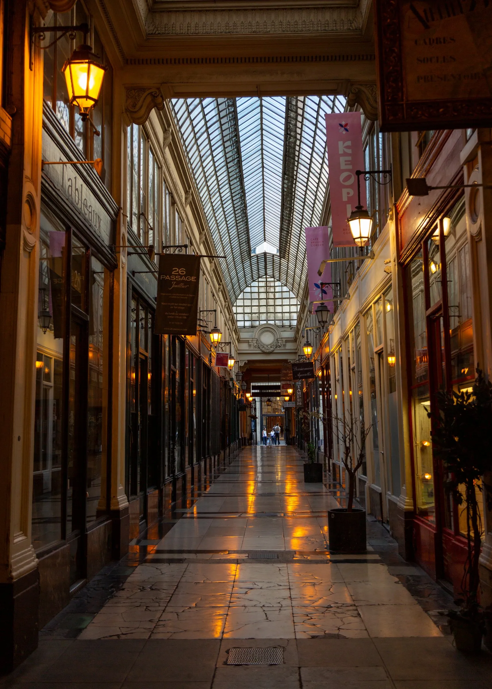 Down the length of a covered passage, lamps still lit