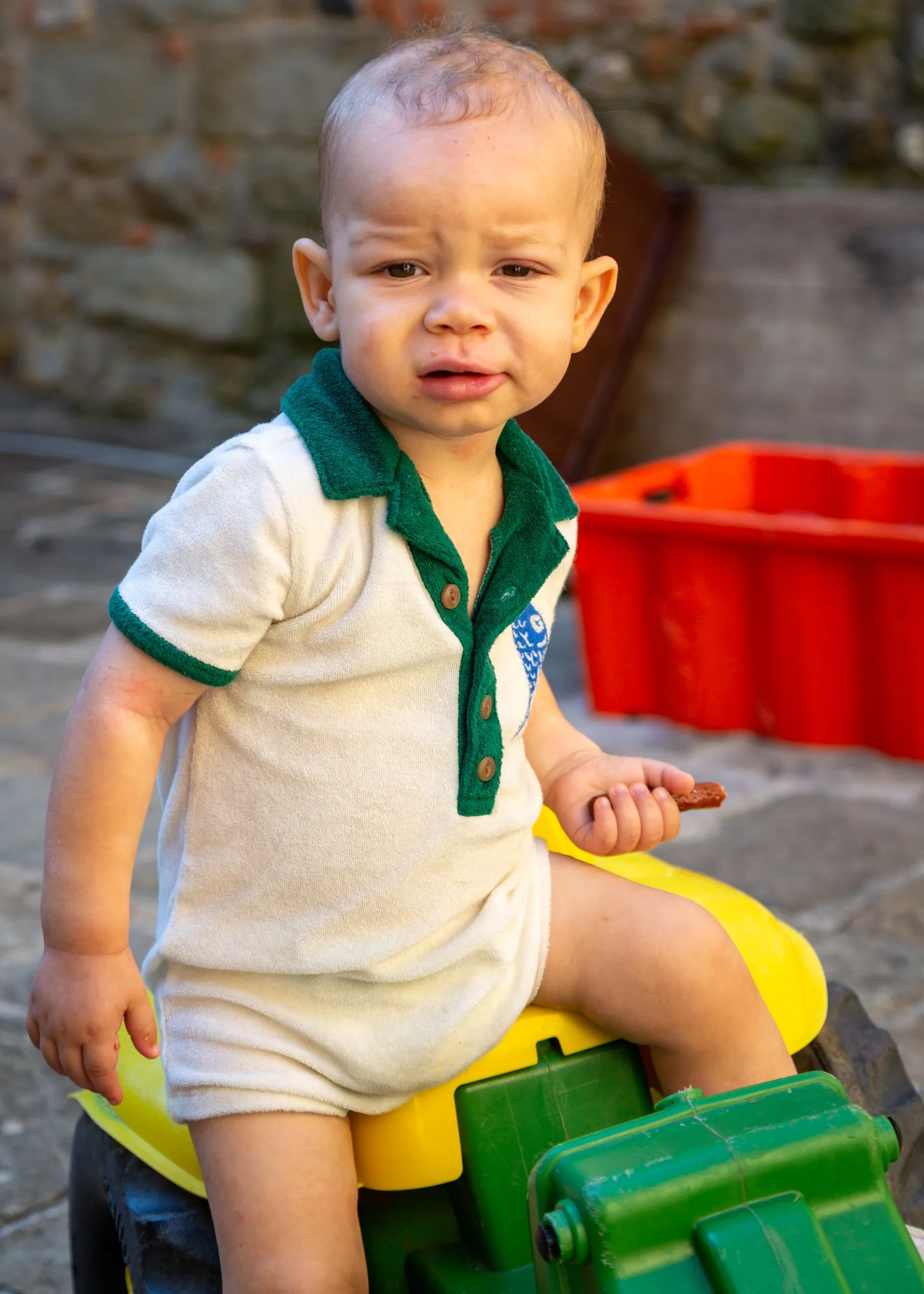 Zavier on a toy tractor in the farm courtyard