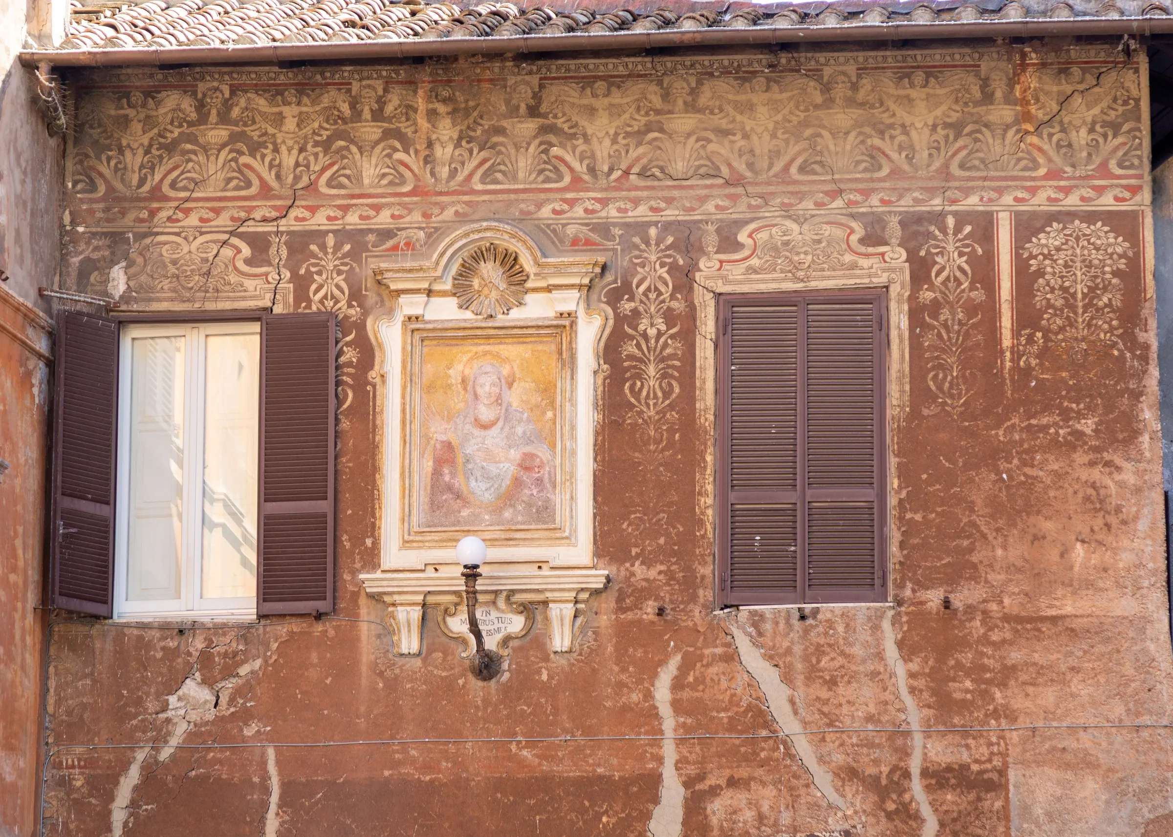 A faded painted façade with a Madonna shrine