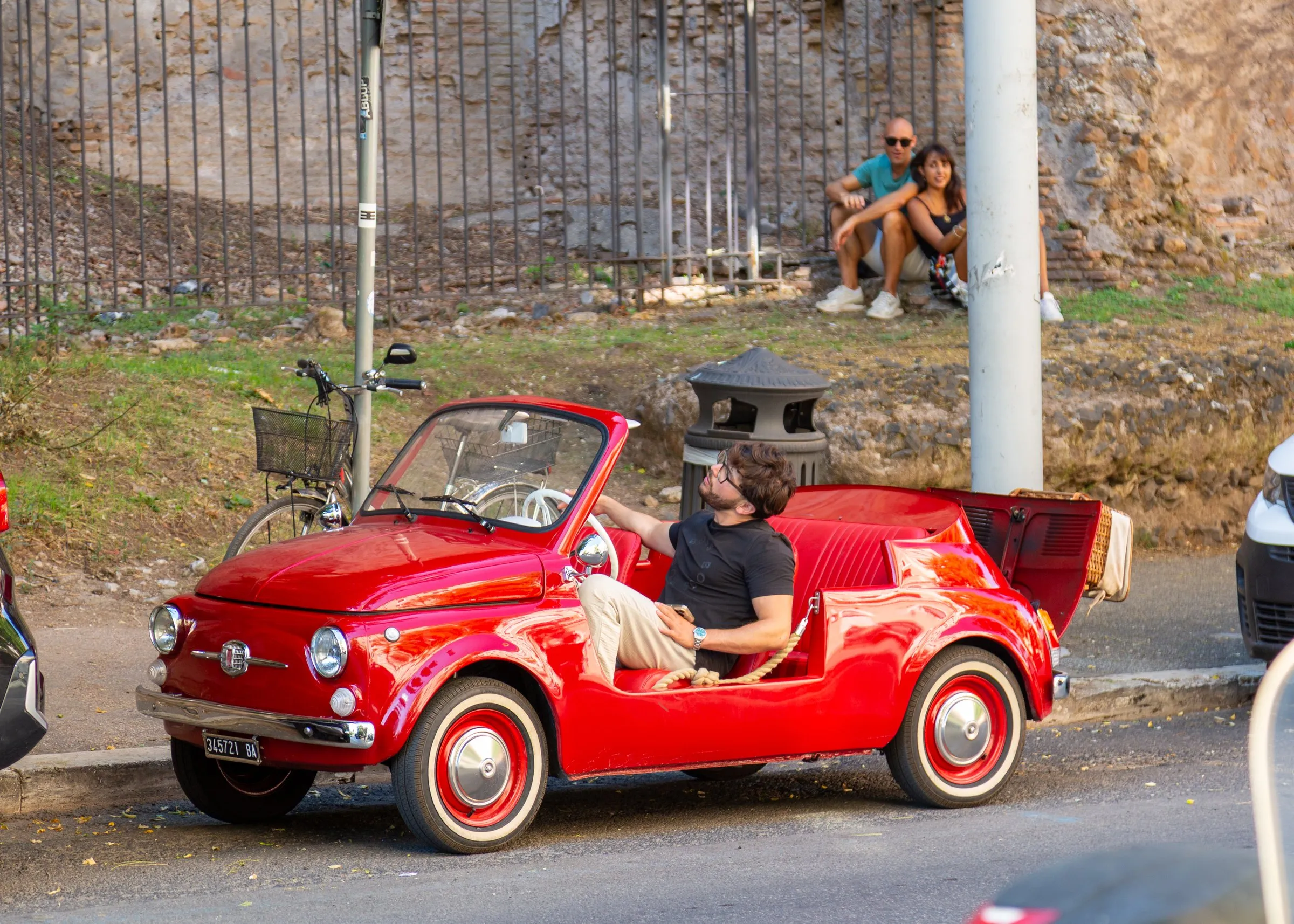 A red Fiat 500 beach car parked on the way to the Vatican